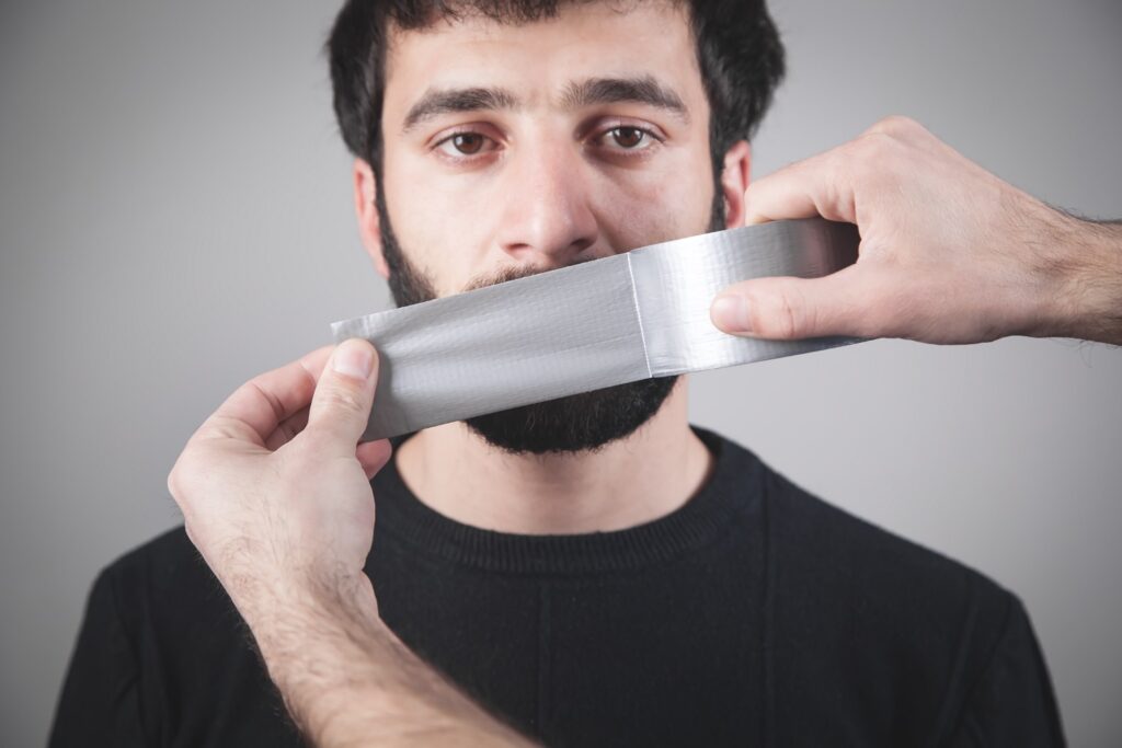 Image of man having tape applied over his mouth
