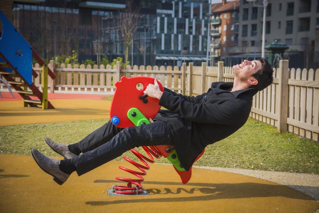 Image of adult man playing on child's playground toy