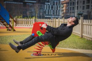 Image of adult man playing on child's playground toy