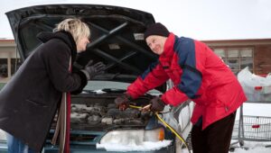 Picture of a man helping to start a woman's car