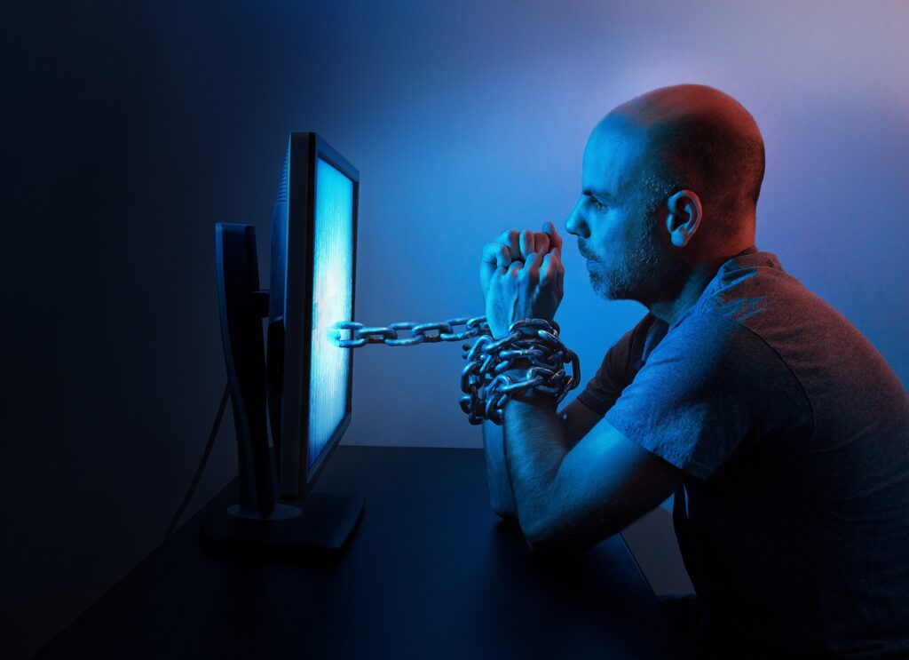 Image of man chained to a computer screen