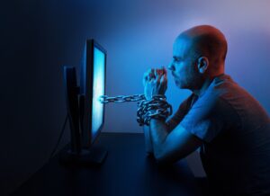 Image of man chained to a computer screen
