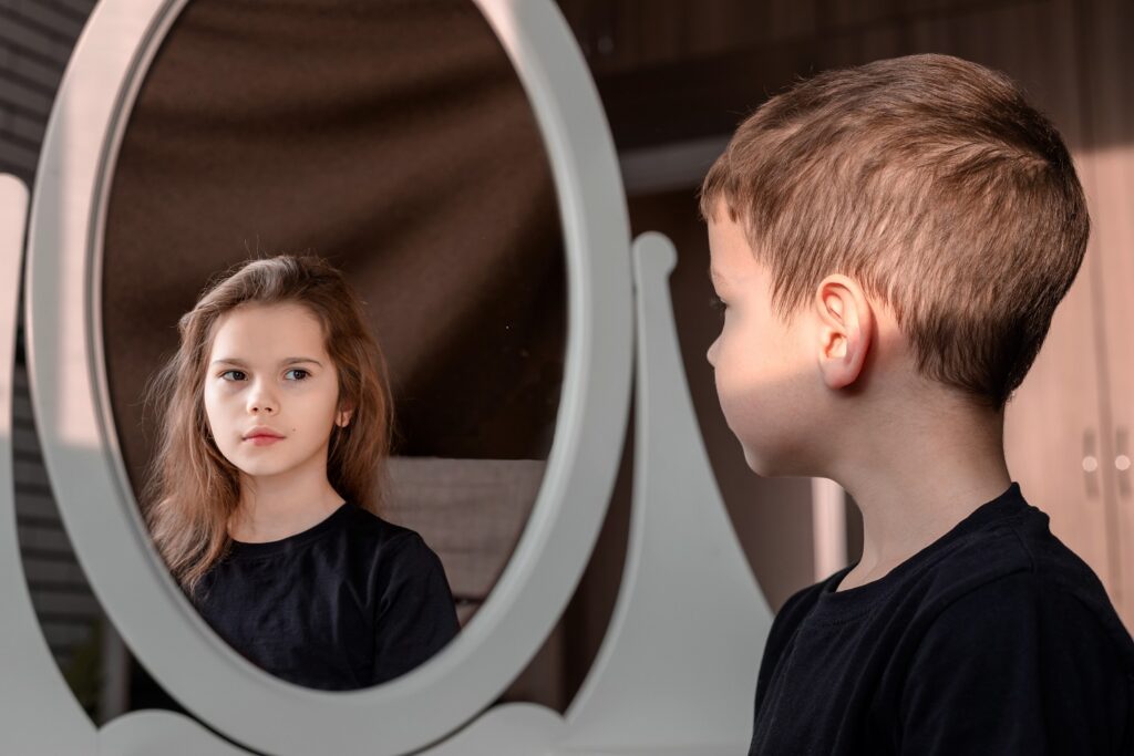 A picture of a boy looking into a mirror and seeing a girl's face.