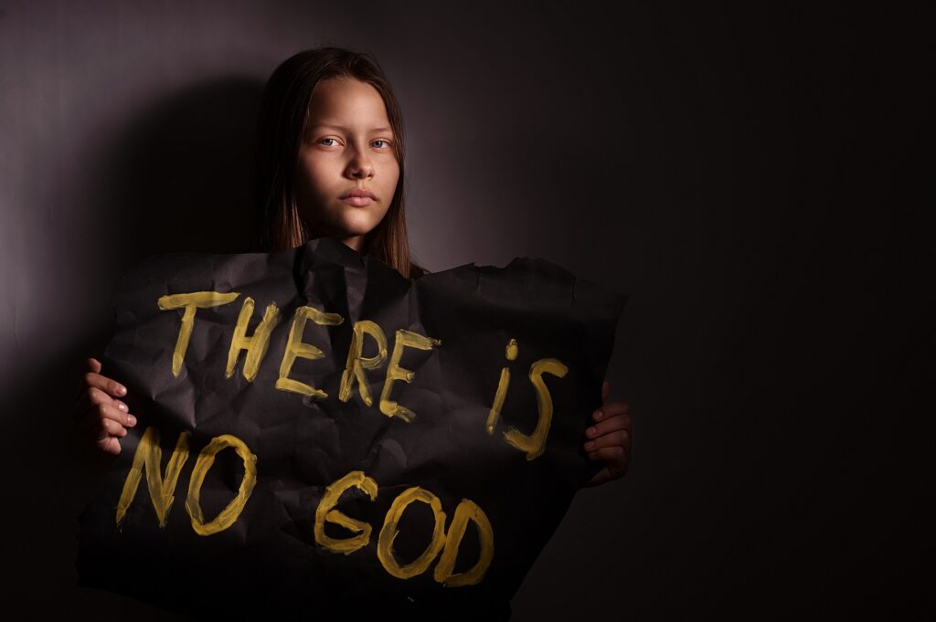 Image of athiest teen holding sign saying "There is no God"