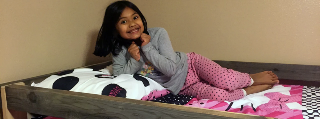 Photo of a girl laying on the top bunk of a bed.